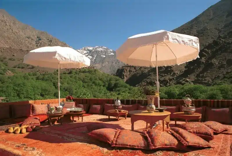 A luxurious patio in Marrakech featuring a table and chairs shaded by umbrellas, ideal for outdoor dining. 