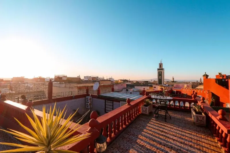 Rooftop terrace of a luxury hotel in Marrakech, offering a panoramic view of the city skyline and surrounding landscape. 