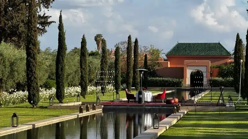 A serene garden featuring a canal and trees, set against the backdrop of a luxury hotel in Morocco.
