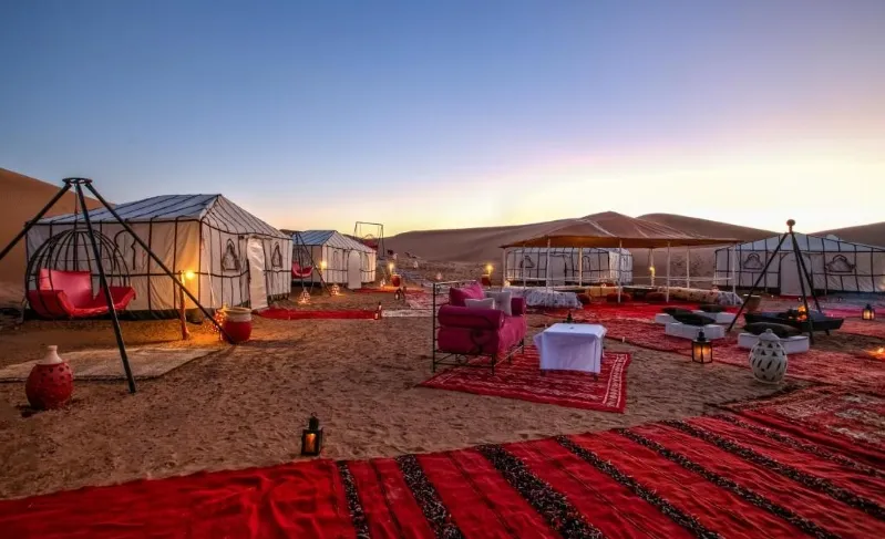 Luxury tents arranged in the sandy desert, showcasing a serene and upscale accommodation experience in Morocco. 