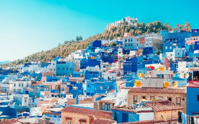 A scenic view of Chefchaouen, Morocco, showcasing its iconic blue buildings and mountainous backdrop. 