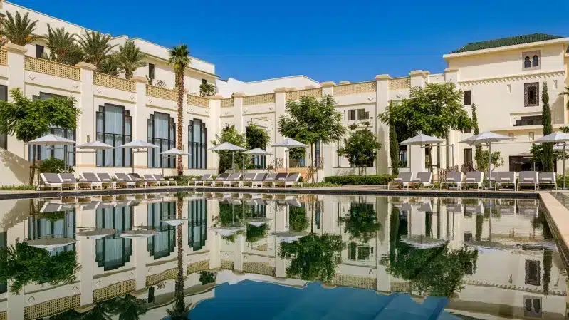 A beautiful pool at a Marrakech riad, surrounded by exotic foliage, epitomizing Morocco Luxury Hotels.
