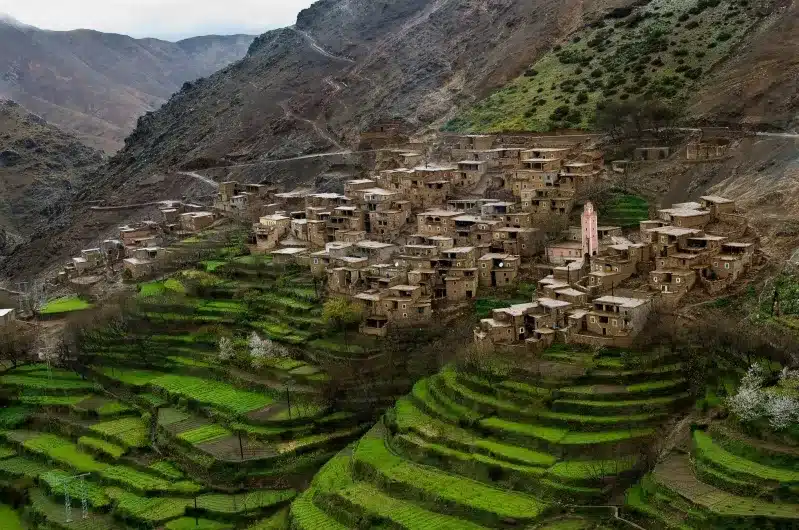 A panoramic view of the village of Atlas in Morocco, showcasing traditional Amazigh architecture and surrounding mountains.