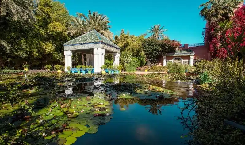 Lush garden of the Alhambra Palace in Marrakech, Morocco, showcasing vibrant plants and intricate pathways.
