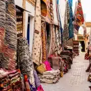 Narrow alley in Morocco with vibrant rugs on the ground, highlighting the need for women's safety.