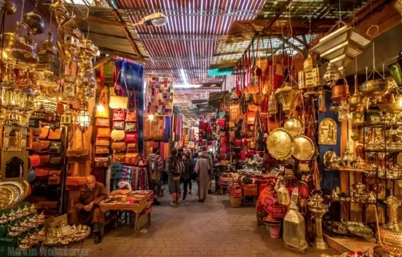 Vibrant Marrakesh market scene showcasing colorful textiles, spices, and bustling shoppers, embodying the Moroccan dream.