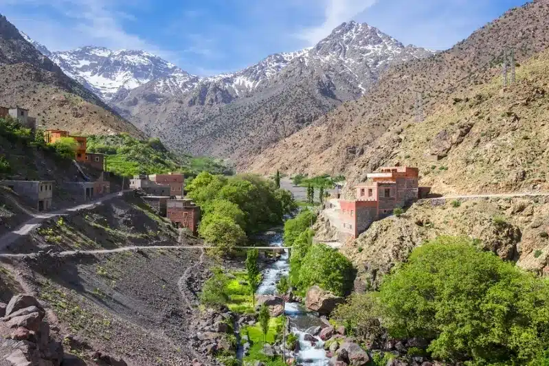 Scenic view of the Atlas Mountains, a river, and a small village, highlighting attractions near Marrakech.
