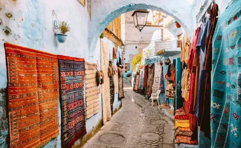 A narrow Moroccan dream alley adorned with vibrant rugs and carpets, showcasing a colorful tapestry of culture and craftsmanship.