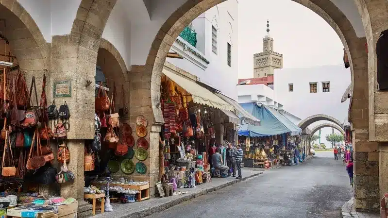 A bustling narrow street in Casablanca lined with shops and people exploring unique local attractions.