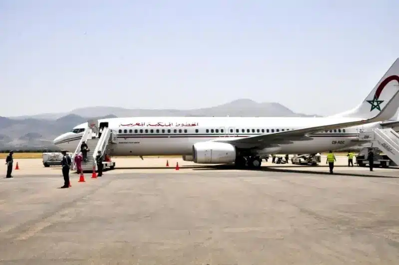 An airplane parked on the tarmac with people gathered around, promoting flights from the USA to Morocco.