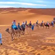 A group of travelers riding camels across the sandy dunes of the Sahara Desert in Morocco.