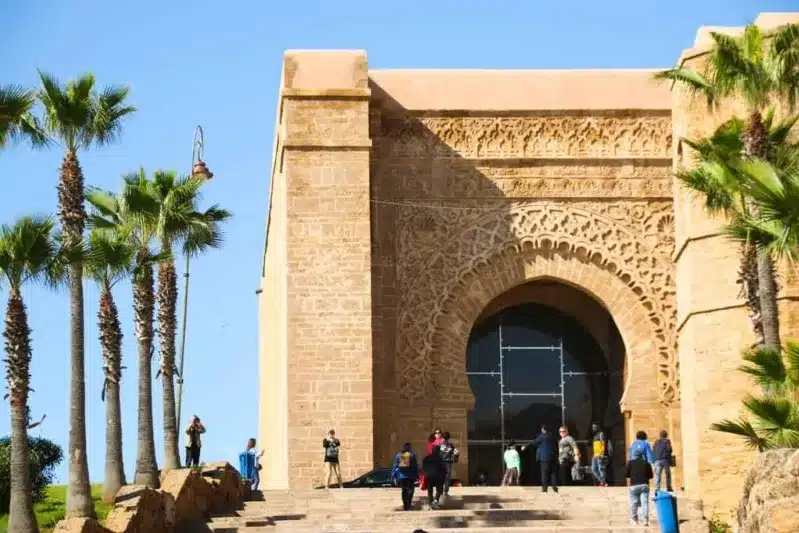 People ascend steps leading to an arched entrance of a building, a notable site in Rabat.