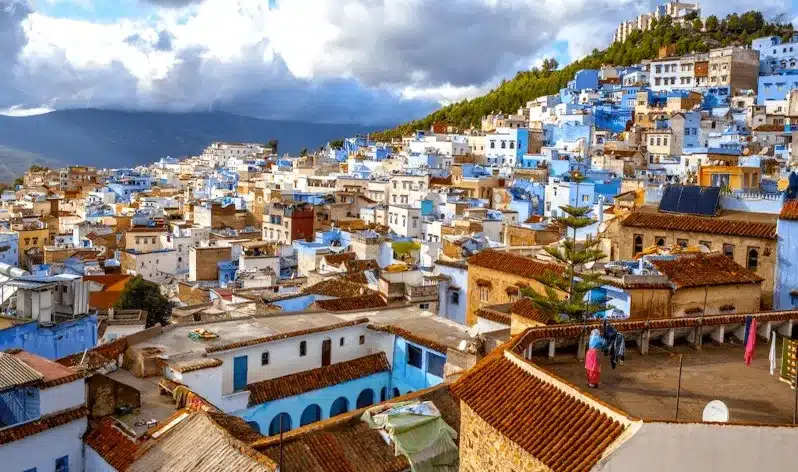 Scenic view of Chefchaouen, Morocco, showcasing its iconic blue buildings, promoted by a Tangier travel agency.