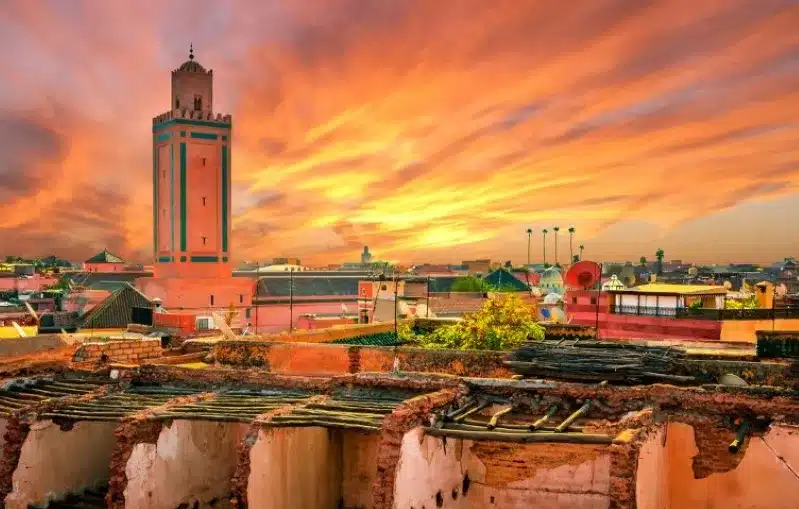 Sunset over Marrakesh, Morocco, showcasing vibrant colors illuminating the city skyline, promoted by a Casablanca travel agency.