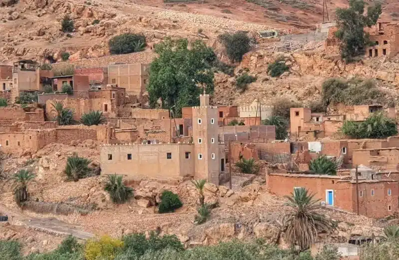 A Berber village in Morocco, featuring a few traditional buildings set against a vast desert landscape. 