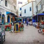 A street scene featuring tables and chairs outside an old building, highlighting a popular spot in Essaouira.