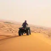 A person riding an ATV through the desert during an 8-day tour in Morocco, surrounded by sandy dunes and clear skies.