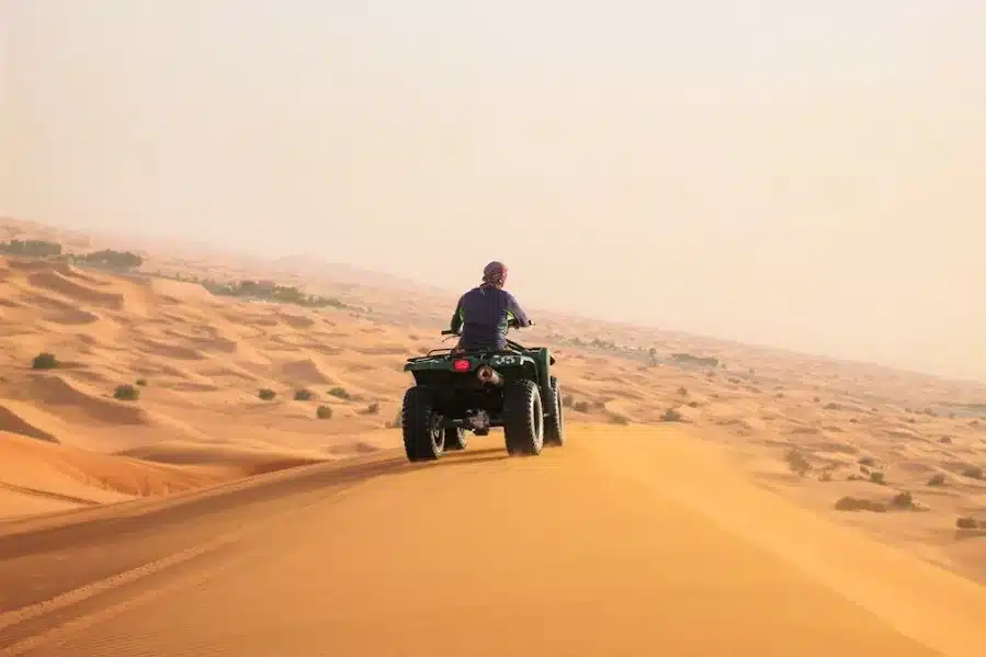 A person riding an ATV through the desert during an 8-day tour in Morocco, surrounded by sandy dunes and clear skies.