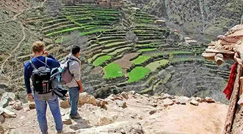 Two hikers with backpacks ascend a steep path during an 8-day tour in Morocco.
