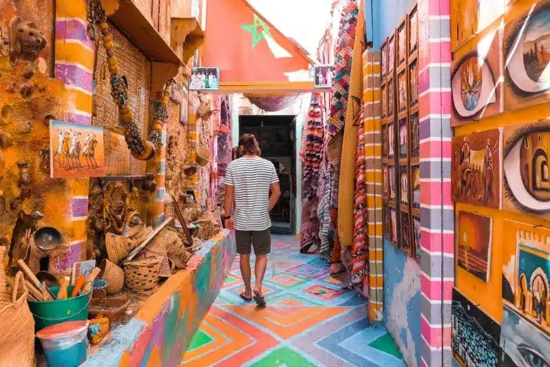 A man strolls through a vibrant alleyway, showcasing the colorful streets of Morocco, a top travel destination.