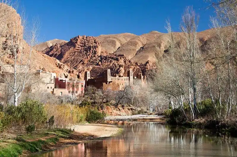 A river flows through a valley, framed by mountains, showcasing the natural beauty of Morocco on a guided tour.
