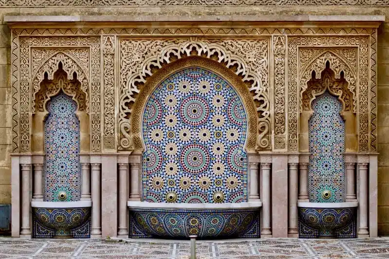 A stunning fountain with intricate designs on the wall, showcasing Moroccan artistry for a tour company promotion.