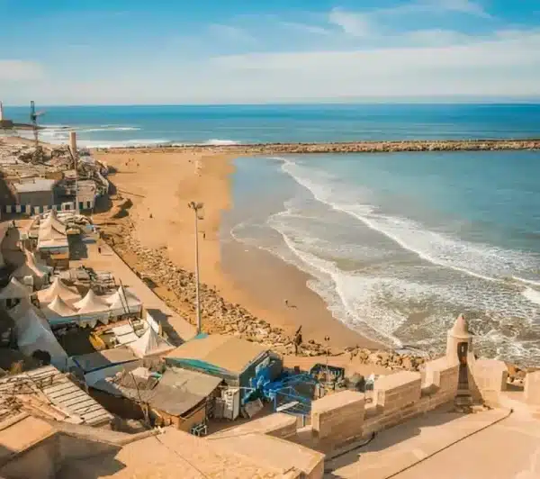 Scenic view of a beach in El Jadida, Morocco, showcasing golden sands and gentle waves under a clear blue sky.