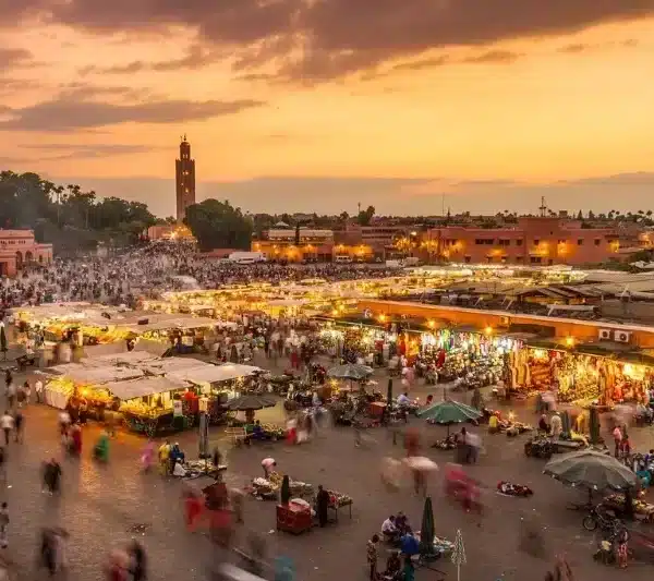 Sunset over Marrakech, with the silhouette of Jbel Saghro mountains in the background, casting a warm glow on the city.