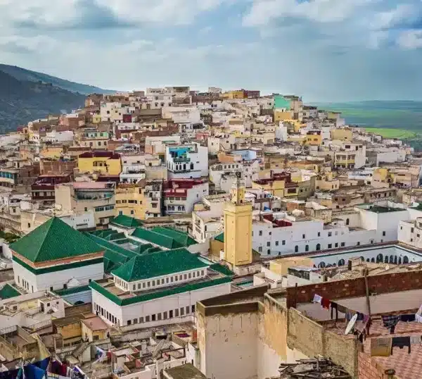 Scenic view of Chefchaouen, Morocco, showcasing its iconic blue buildings and mountainous backdrop during a Volubilis Day Tour.