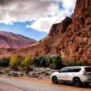 A white SUV parked on a mountain road, showcasing the scenic landscape of Morocco.