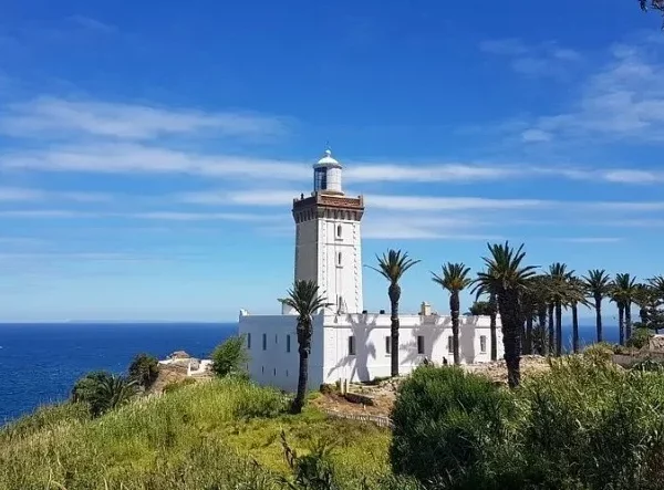 A coastal lighthouse surrounded by palm trees, symbolizing a scenic day trip to Tangier.