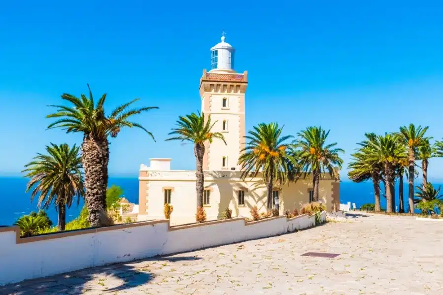 A scenic lighthouse on the coast surrounded by palm trees, representing Tangier Private Tours.