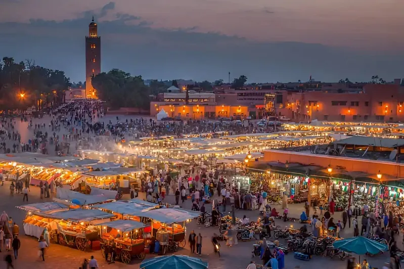 A panoramic view of a Moroccan city nestled in the desert, showcasing traditional architecture against a sandy landscape.