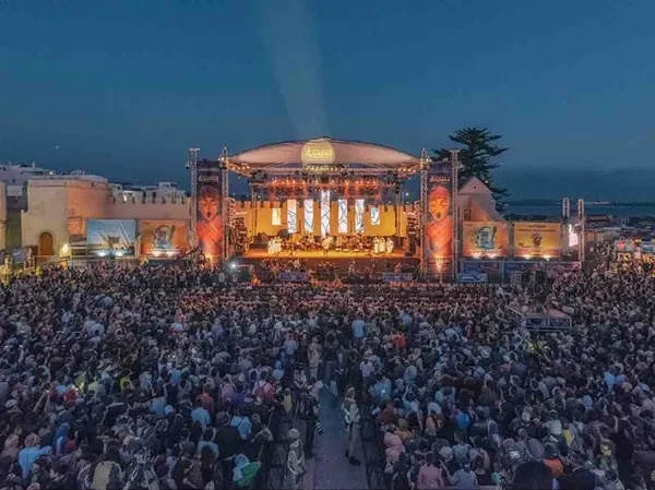 A large crowd enjoying the Dinner Show with Gnaoua at a vibrant music festival.
