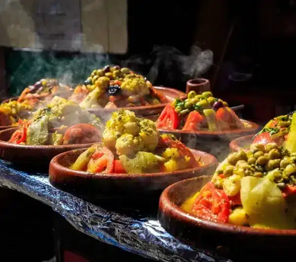 A line of bowls filled with various foods, showcased at the Dinner Show with Gnaoua event.