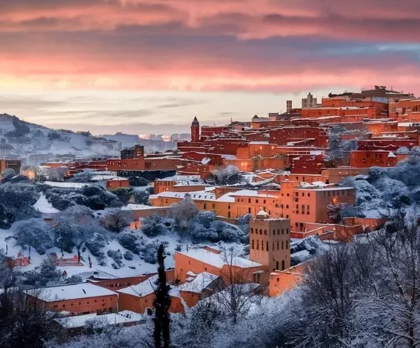 A snowy mountain town in Morocco featuring charming red-roofed houses under a clear blue sky.
