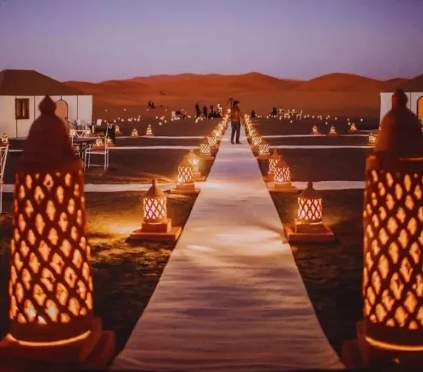 A wedding ceremony in the desert, illuminated by lit candles, set against the backdrop of Ouarzazate's stunning landscape.