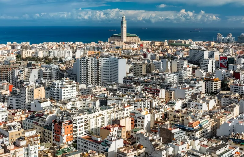 Aerial view of Casablanca, Morocco, showcasing the city's architecture and coastline against a clear blue sky.