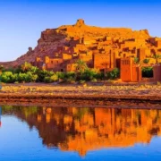 A camel stands in the desert with a castle in the background, symbolizing Morocco holidays.