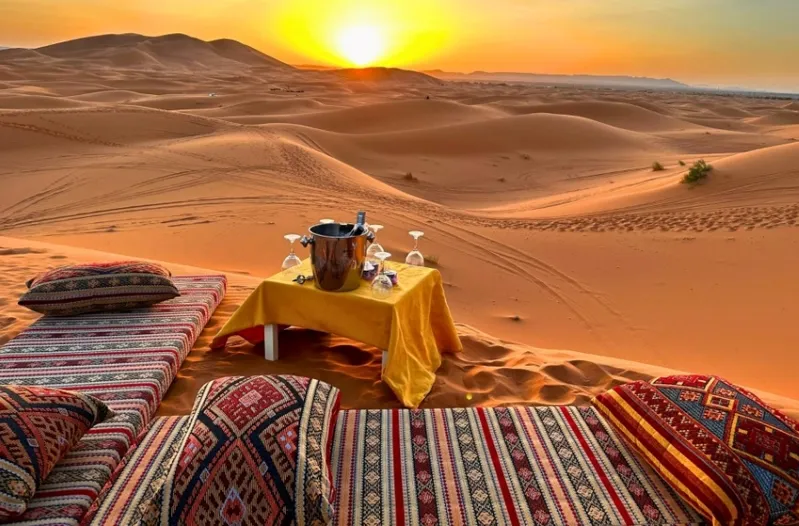 Sunset over the Morocco Sahara Desert Tours , showcasing vibrant orange and purple hues against vast sand dunes.