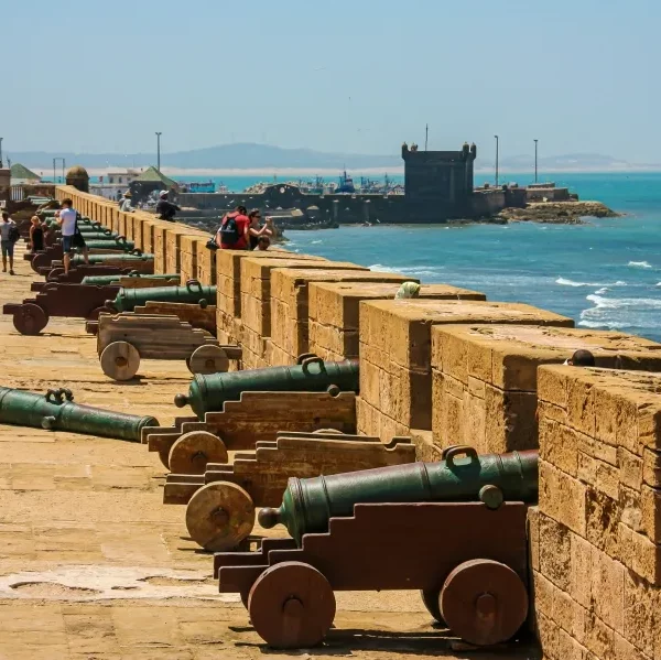 A row of historic cannons positioned along a stone wall in Evisa, Morocco, showcasing military architecture.