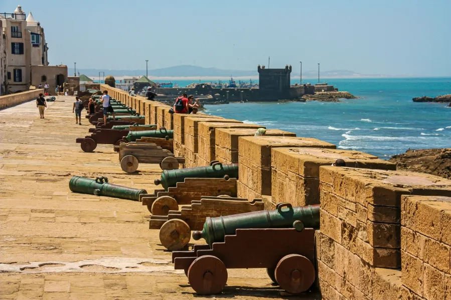 A row of historic cannons positioned along a stone wall in Evisa, Morocco, showcasing military architecture.