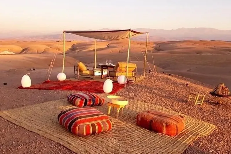 A tent in the desert with a table and chairs, set up for Marrakech Desert Tours, surrounded by sandy dunes.