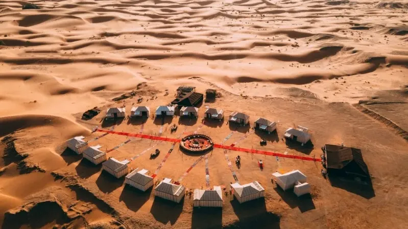 Aerial view of a desert camp featuring several tents, showcasing the vast landscape of Marrakech Desert Tours.