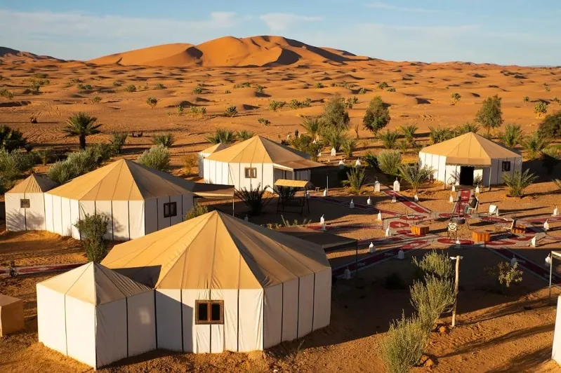 A group of tents set up in the desert, with majestic mountains visible in the background, ideal for desert tours.