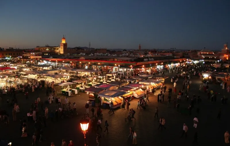 Nighttime market in Marrakech, bustling with vendors and colorful lights, showcasing local crafts and cuisine.
