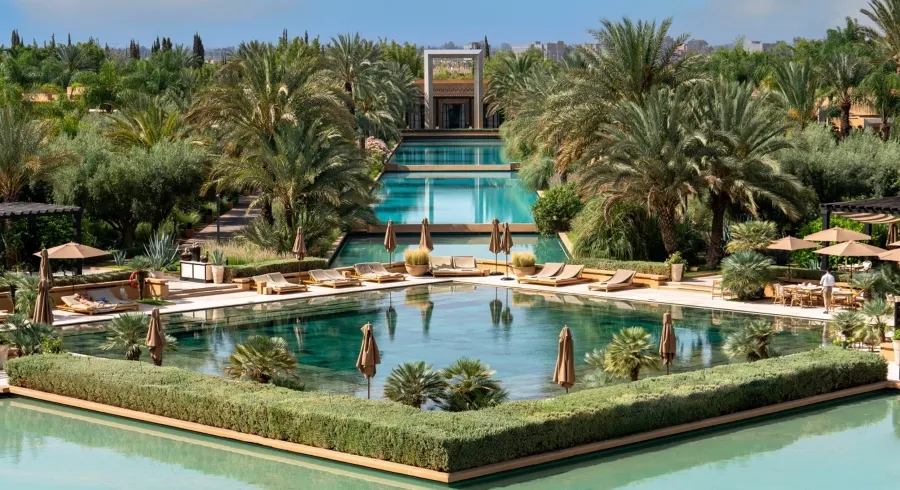 A serene pool surrounded by lush palm trees, set within a luxurious resort in Marrakech.