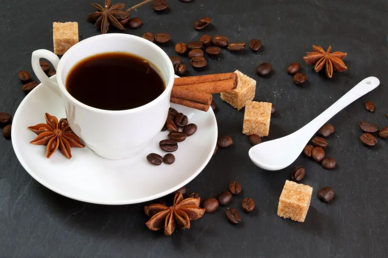 A close-up of coffee and spices arranged on a black slate background, evoking the essence of a Moroccan drink.
