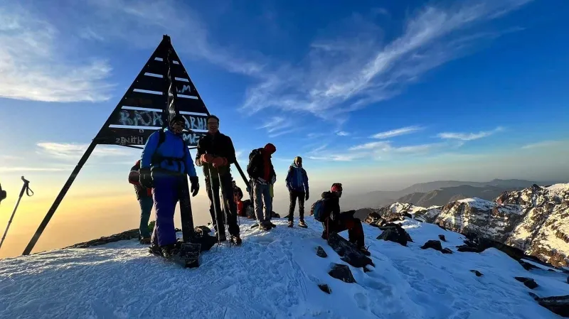 A group of trekkers stands atop a mountain in the Atlas Mountains of Morocco, enjoying the panoramic view.During trekking in Morocco Atlas Mountains 