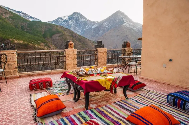 A rooftop table set against the backdrop of the Atlas Mountains in Morocco, showcasing a scenic trekking experience.